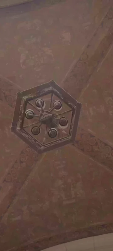 A view looking straight up at an ornate, painted, vaulted ceiling with a central, antique light fixture.