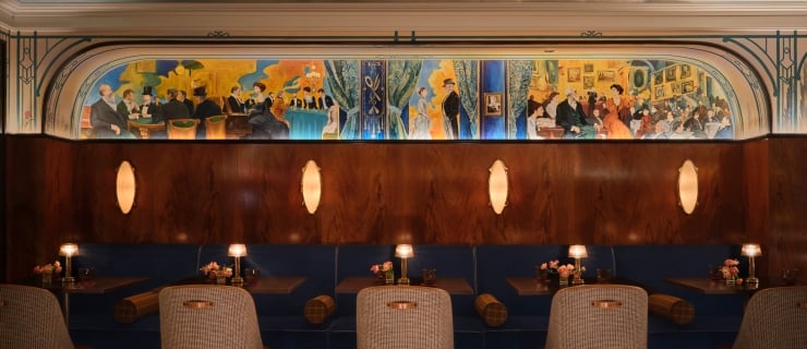 Banquette seating beneath an ornate mural and dim lighting