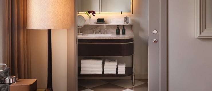 A pocket door opening to a handsome marble bathroom with vanity and backlit mirror