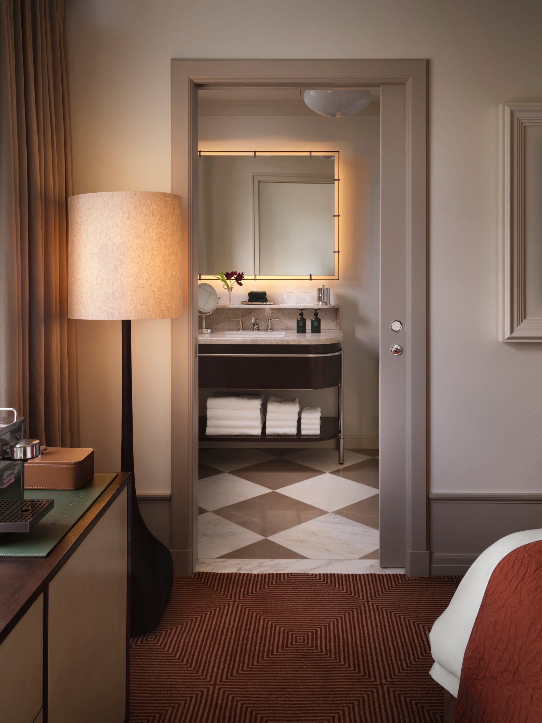 A pocket door opening to a handsome marble bathroom with vanity and backlit mirror