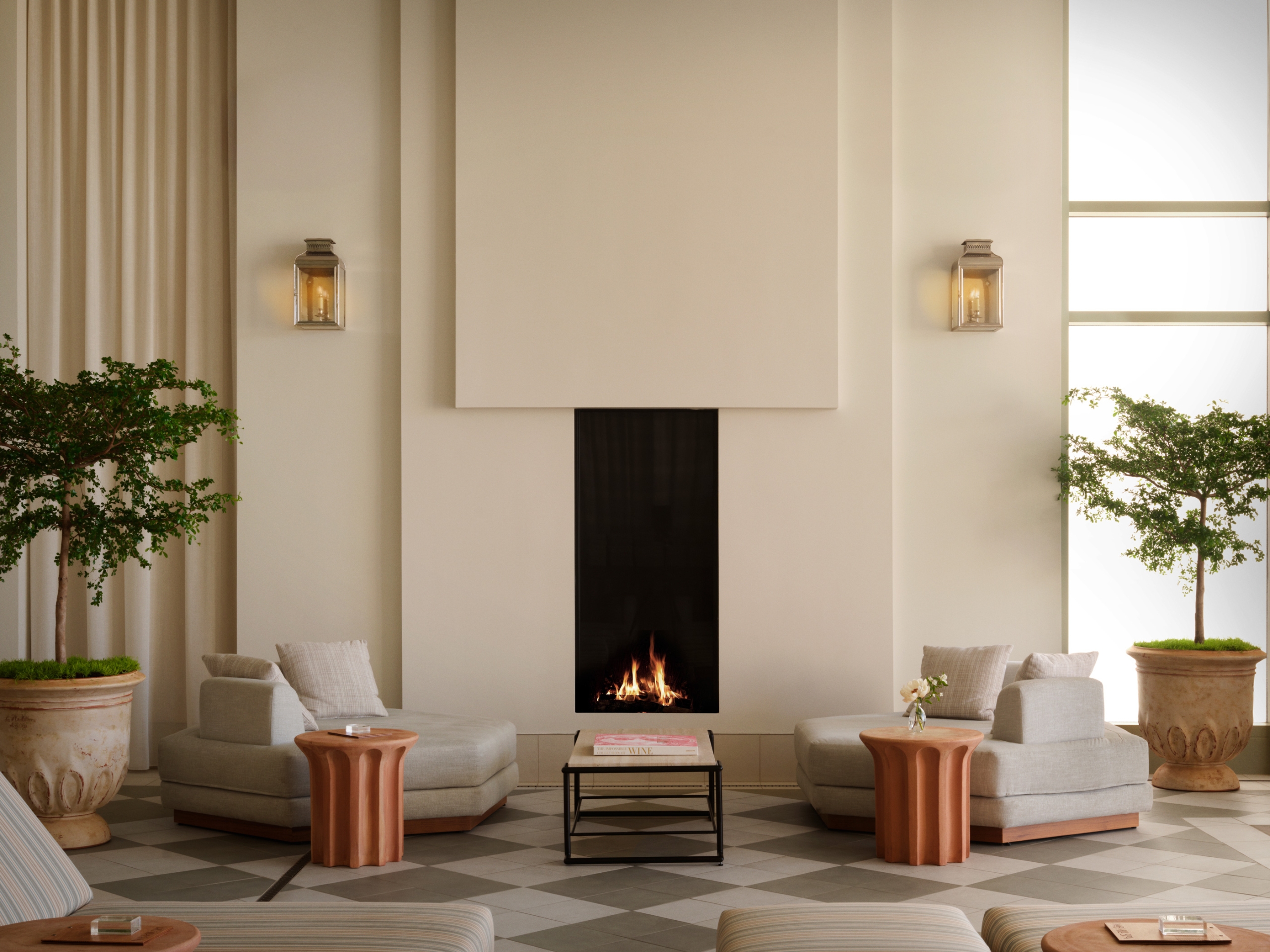 A plaster fireplace with two large lounge seats and a coffee table in a sunny atrium.
