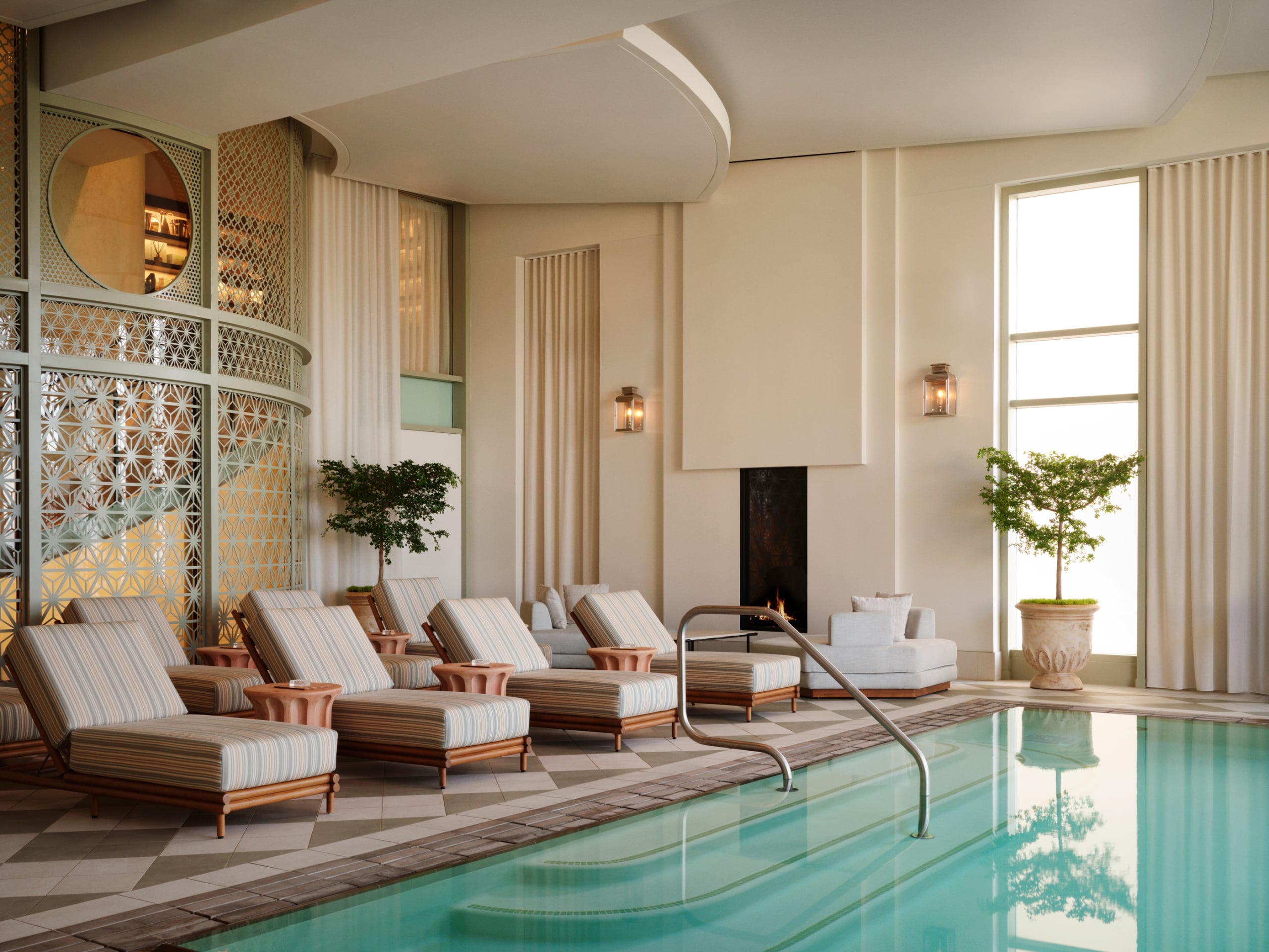An indoor luxury swimming pool area with a row of cushioned chaise lounges lined up along the water's edge