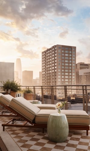 Three sun loungers on a patterned outdoor rug on a terrace overlooking San Francisco