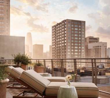 Three sun loungers on a patterned outdoor rug on a terrace overlooking San Francisco
