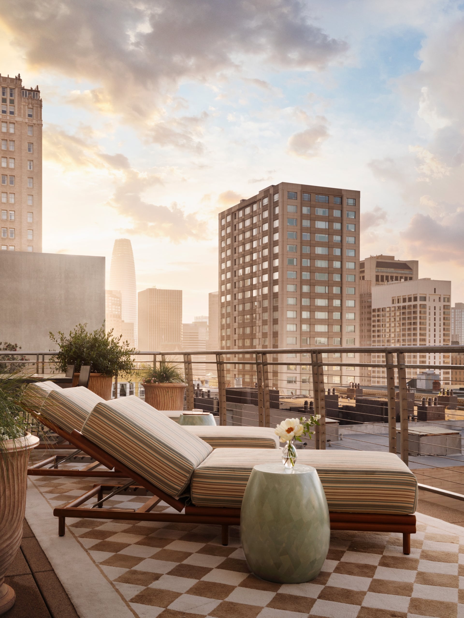 Three sun loungers on a patterned outdoor rug on a terrace overlooking San Francisco