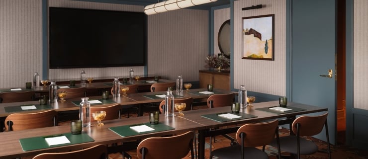 A blue ceiling, gray wall room with warm carpeting and tables set up for a meeting.