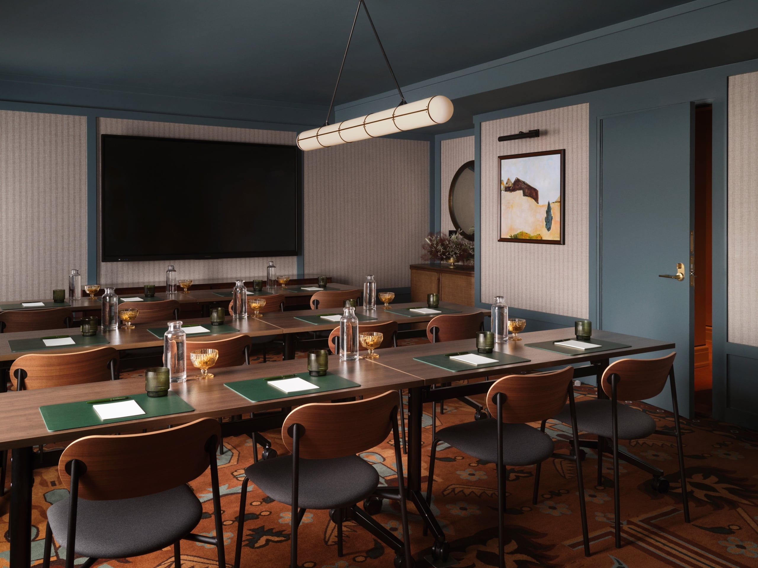 A blue ceiling, gray wall room with warm carpeting and tables set up for a meeting.