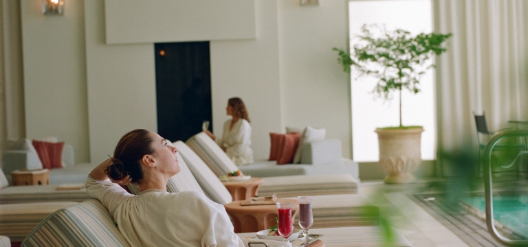 A woman relaxes in a white robe on a striped chaise lounge