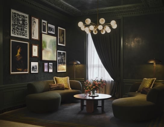 A deep green room with two plush sofas and a gallery wall