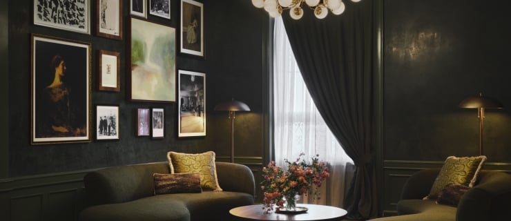 A deep green room with two plush sofas and a gallery wall