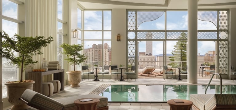 indoor pool room featuring floor-to-ceiling windows that provide an expansive view of a city skyline