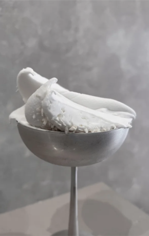 scoop of white gelato served in a small metallic, pedestal-style cup